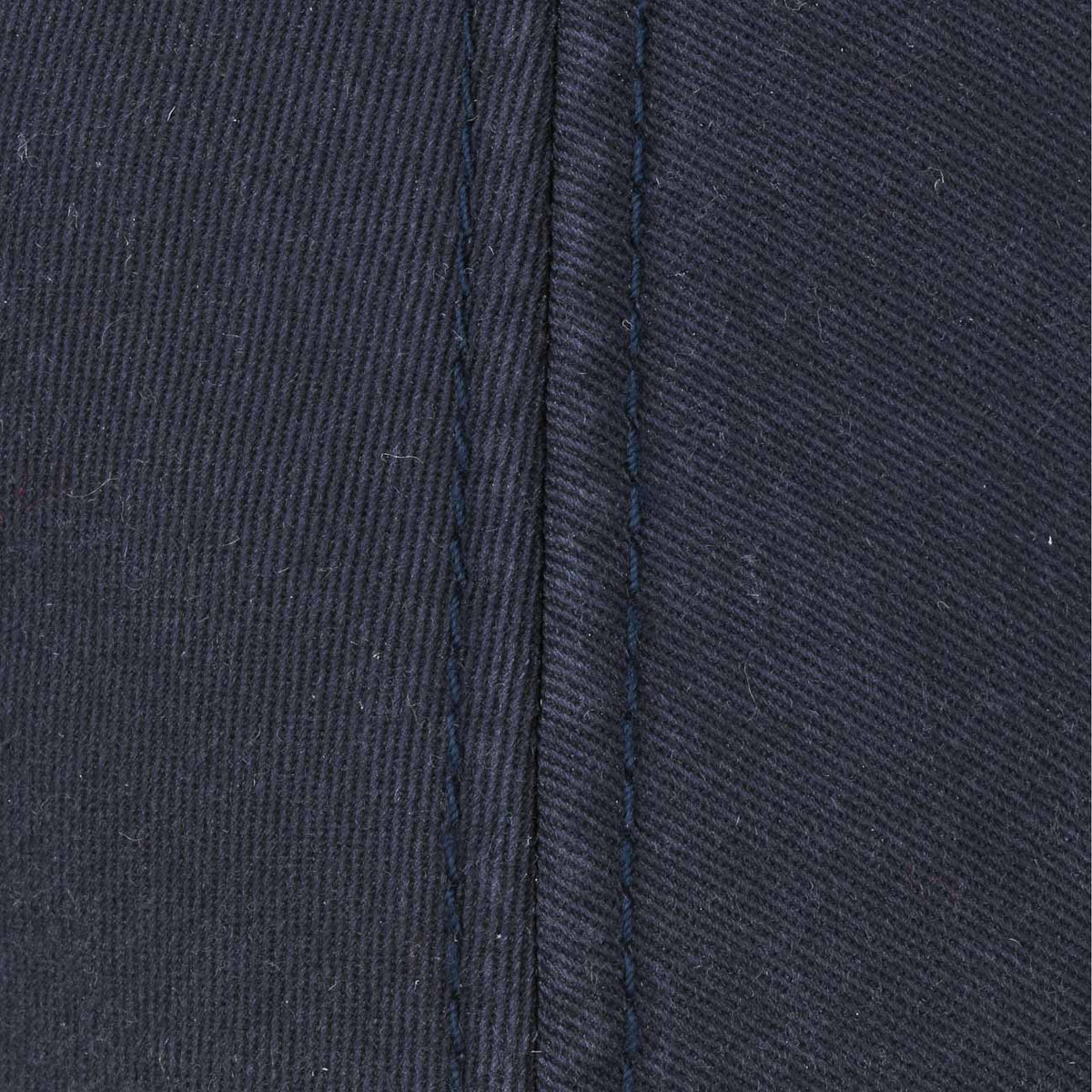Macro du sergé de coton bleu marine et de la couture centrale de la calotte