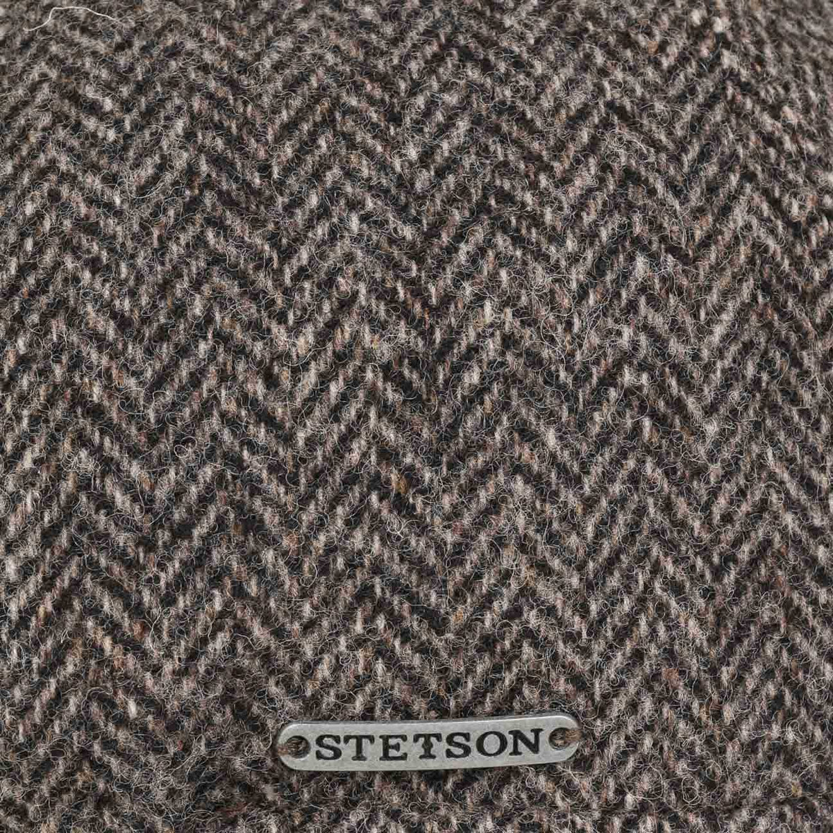 Macro du tissage à chevrons gris-brun et de la plaque métal au centre