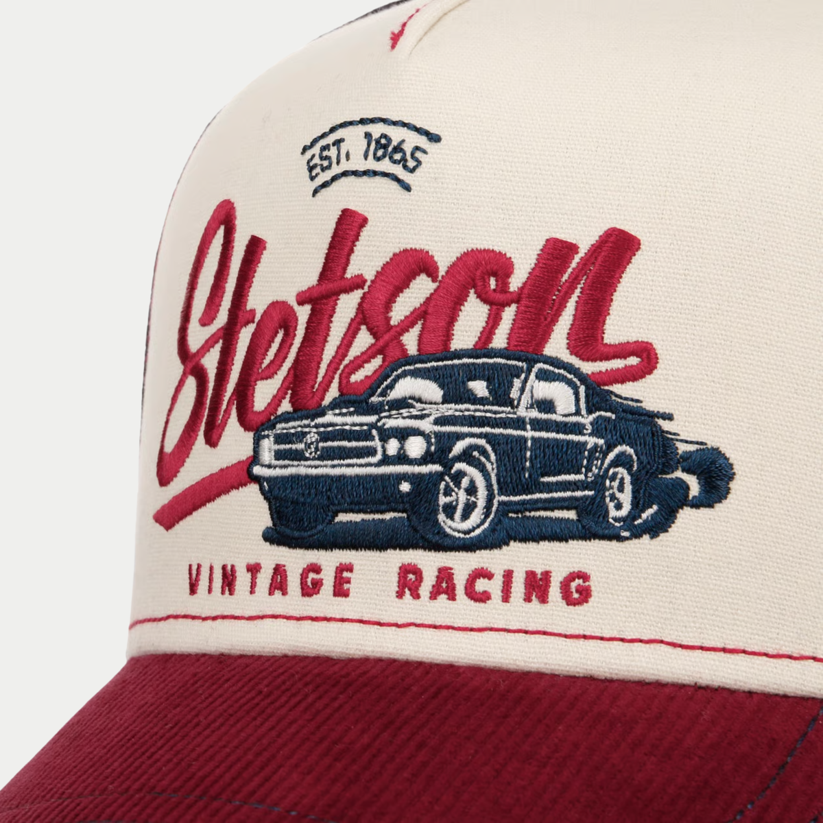 Gros plan de la broderie Stetson Est. 1865 et de la voiture de course Vintage Racing sur le devant écru