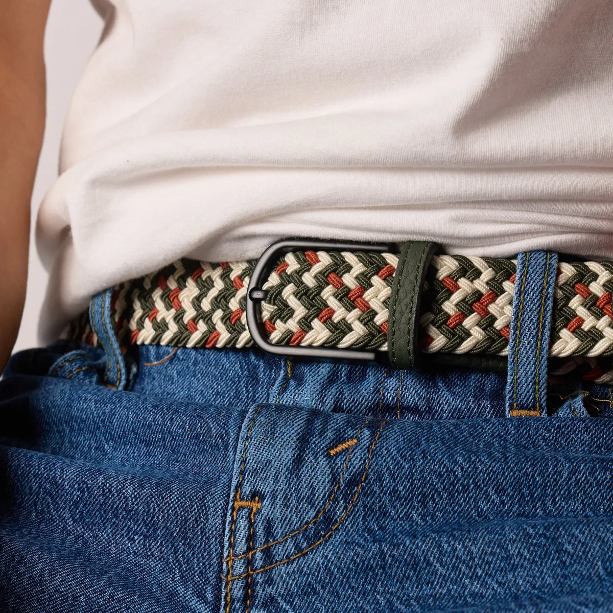 Ceinture Biarritz portée de face dans les passants d'un jean, boucle noire mate et passant en cuir vert olive.
