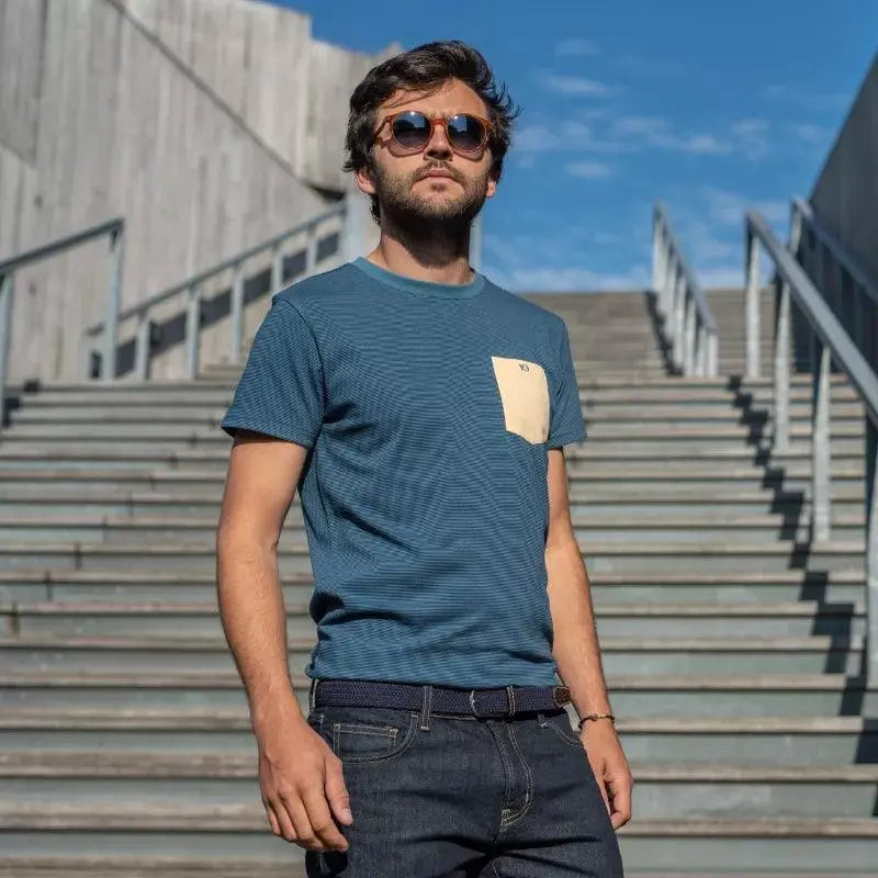 Cadrage en pied dans un escalier : la ceinture Bleu Marine ferme un jean brut, boucle sombre au centre du cadre