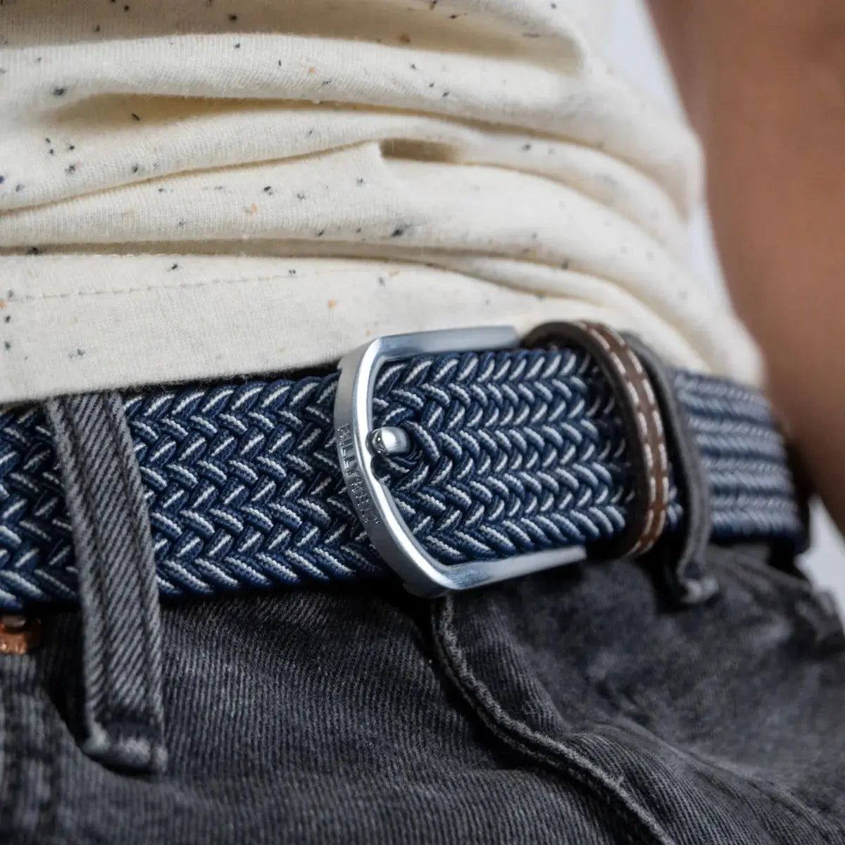 Boucle argent brossé gravée BILLYBELT posée sur les chevrons bleu marine et blanc serrés de la ceinture Bogota