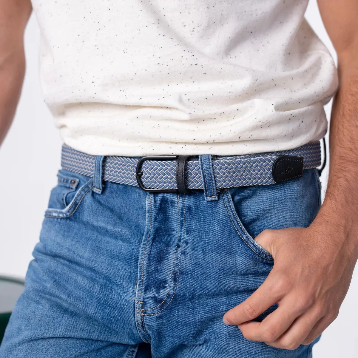 Tressage Chicago bleu jean et écru porté sur un denim bleu moyen, boucle noire mate et patte de cuir noir