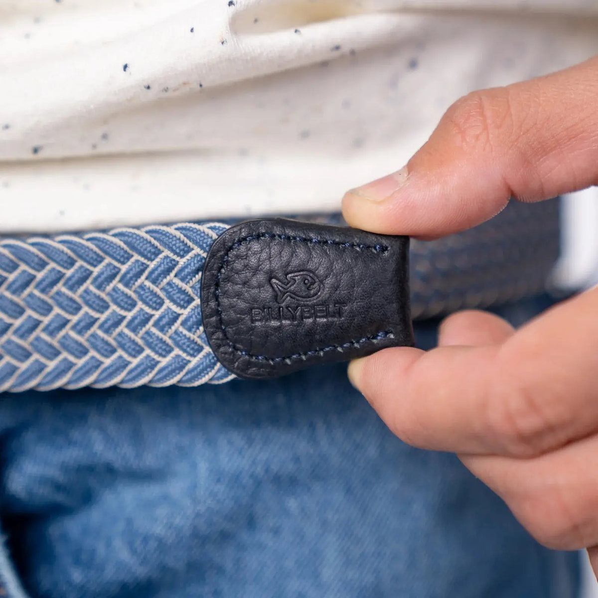Patte de cuir noir grainé au poisson gravé, terminant les chevrons bleu jean et écru de la ceinture Chicago