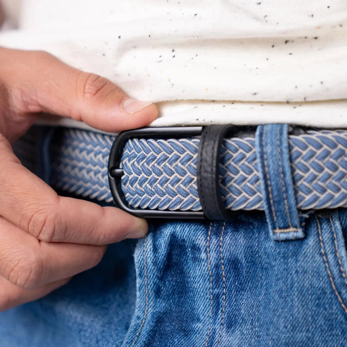 Boucle noire mate ajustée à deux mains sur la tresse Chicago bleu jean et écru, au-dessus d'un jean bleu