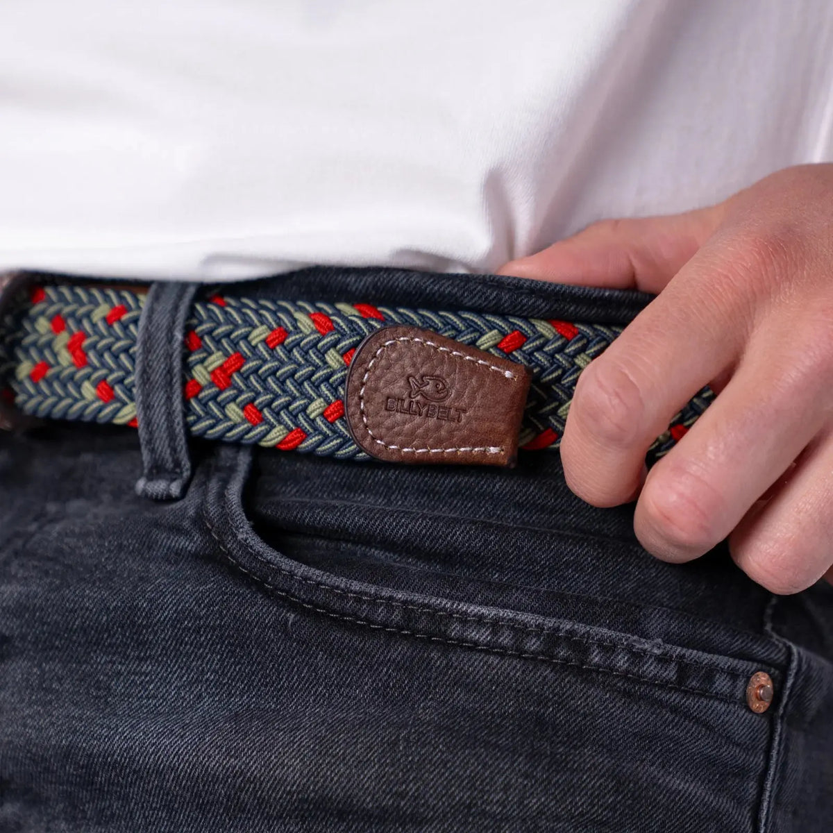 Macro de l'embout en cuir grainé marron du modèle Goteborg, tressage bleu marine, amande et rouge sur jean noir