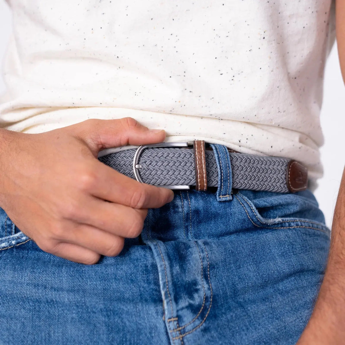 Ceinture Gris Froid gris clair portée sur un jean bleu délavé, boucle argentée et passant de cuir marron