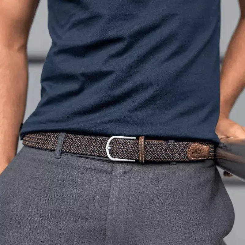 Tressage Havane bleu marine et doré vu à la taille sur un pantalon gris, embout de cuir marron au logo estampé