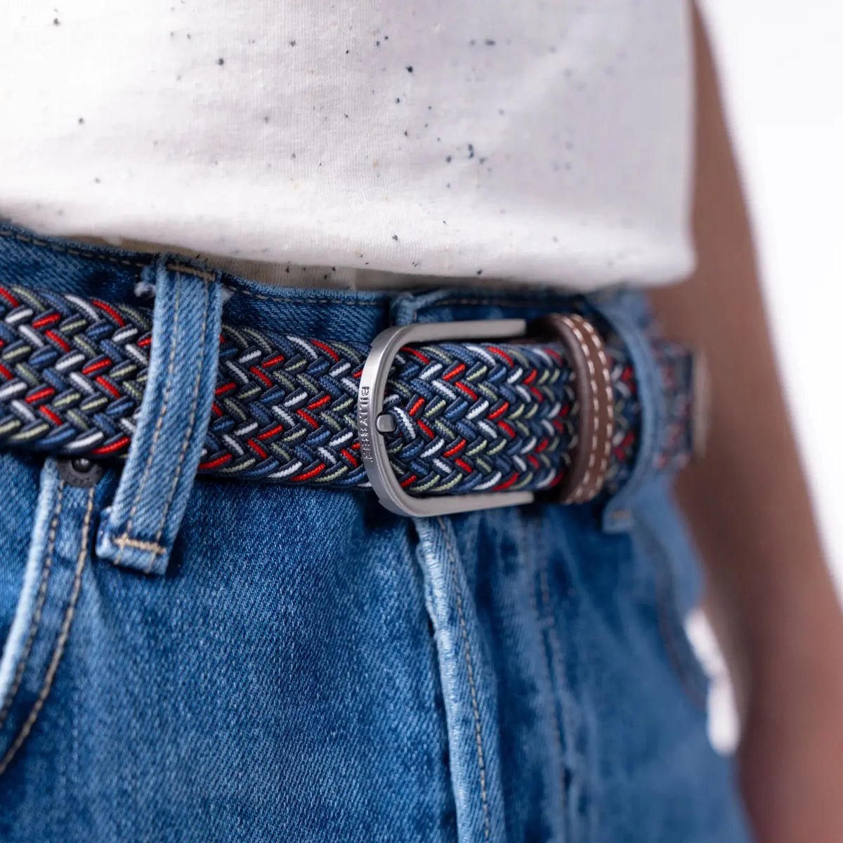 Boucle argentée gravée BillyBelt sur le tressage Istanbul bleu marine, rouge et blanc, porté sur un jean bleu