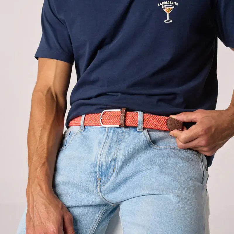 Ceinture tressée corail portée de face sur un jean clair délavé avec un t-shirt bleu marine, vue de trois quarts.