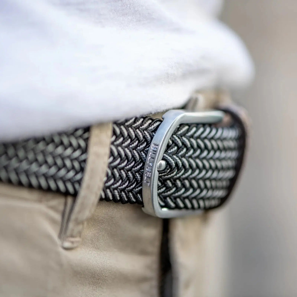 Macro de la boucle argentée gravée BillyBelt sur le chevron noir et blanc du modèle Vienne, sur un chino beige