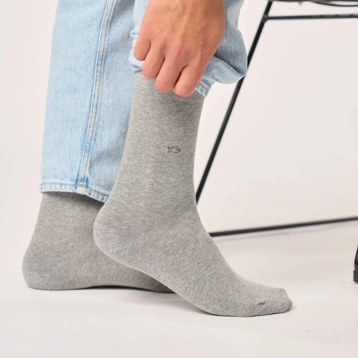 Chaussette gris clair chinée portée sous un jean clair, bord-côte replié et maille finement mouchetée