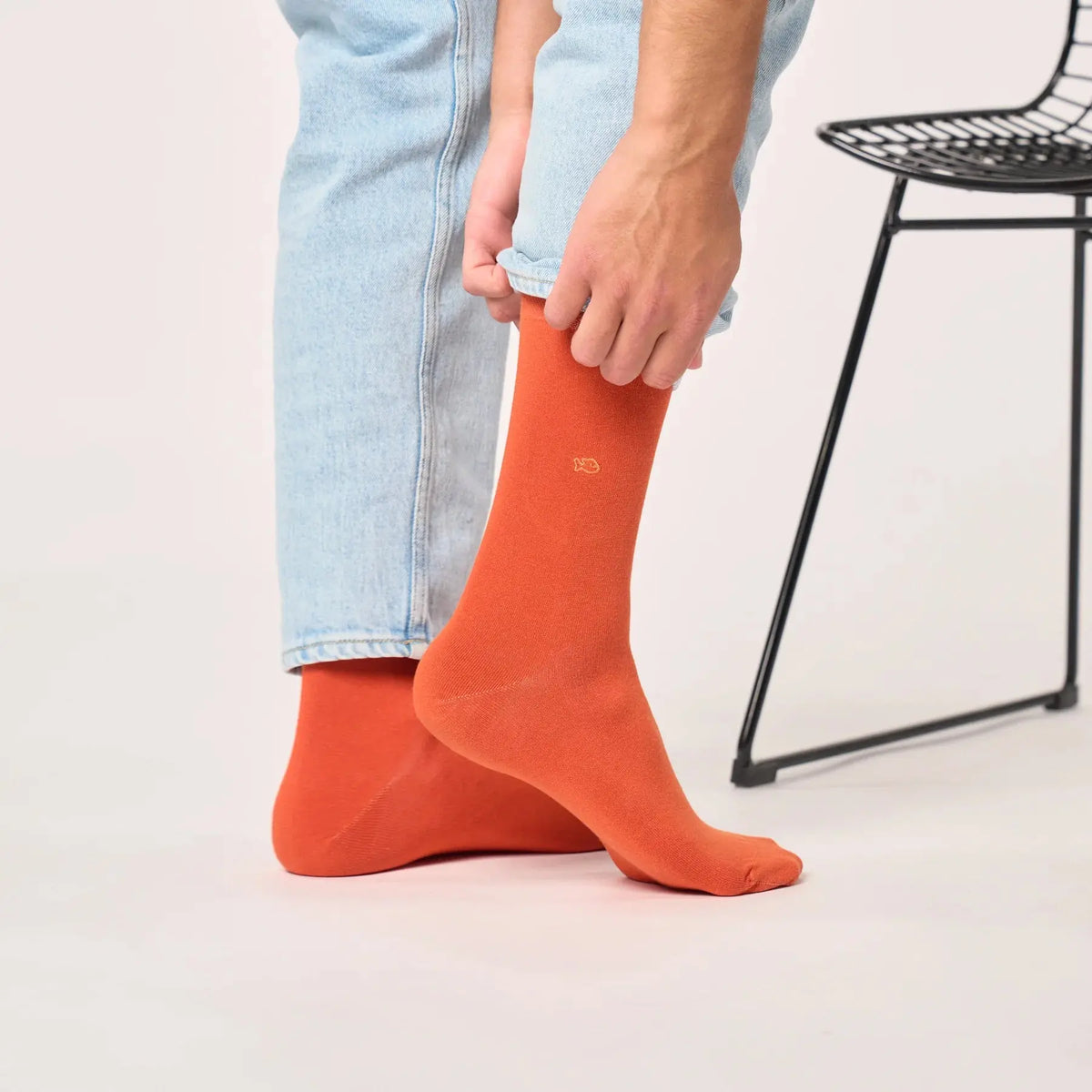 Chaussette orange terracotta portée sous un jean clair, tige droite et maille fine et mate sans motif