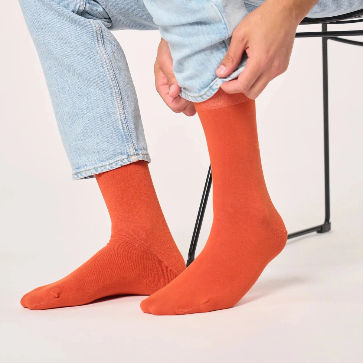 Paire orange terracotta portée jambes repliées, la maille lisse épouse le coup de pied et la pointe arrondie