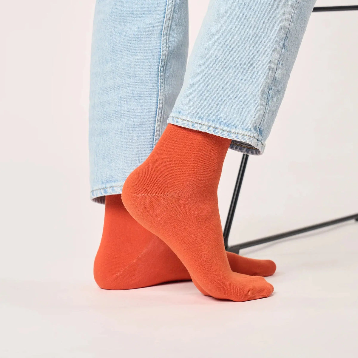 Chaussettes orange terracotta vues de dos sous un jean clair, talon et tige dans un orange franc et soutenu