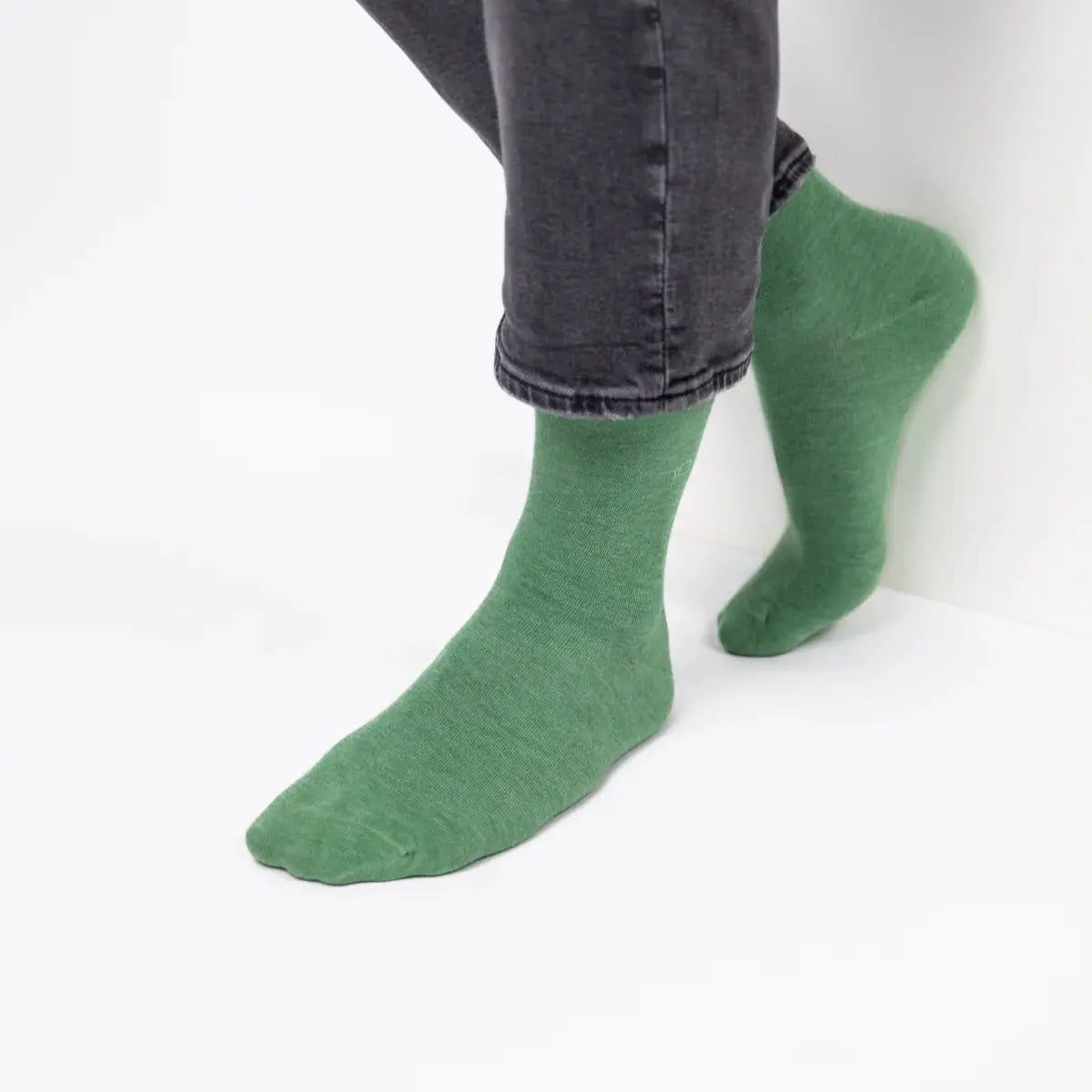 Chaussettes vert amande portées avec un jean gris, la couleur se densifie sur le coup de pied et la tige