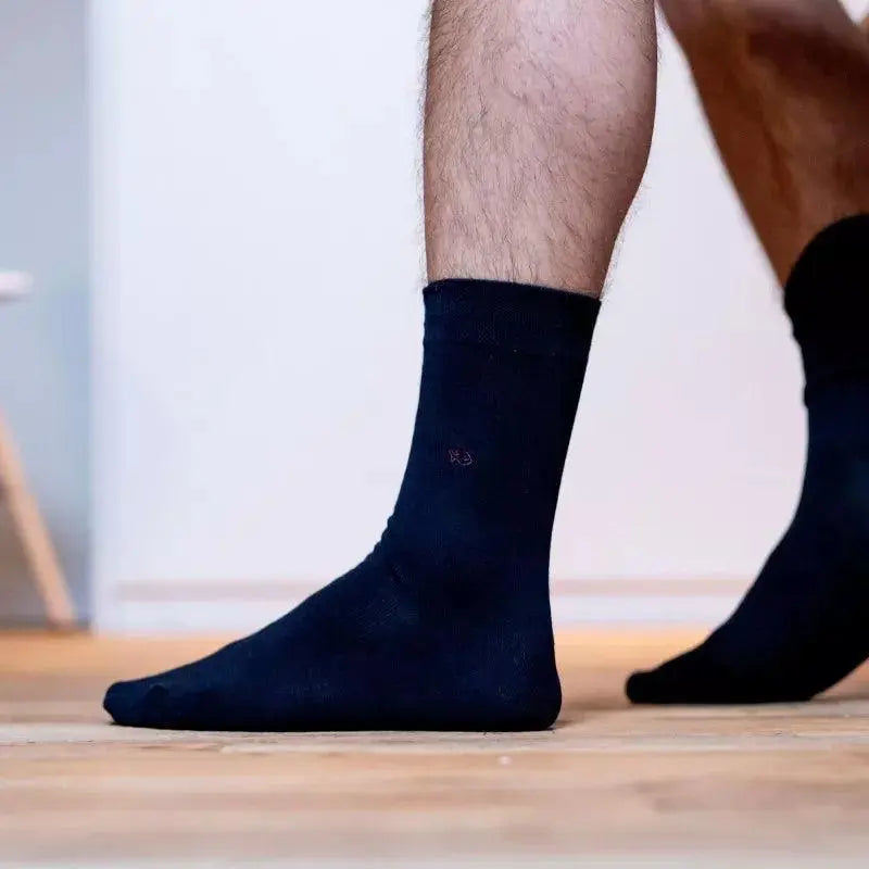 Chaussette Bleu Marine portée de profil sur un parquet, tige souple mi-mollet et maille de coton unie