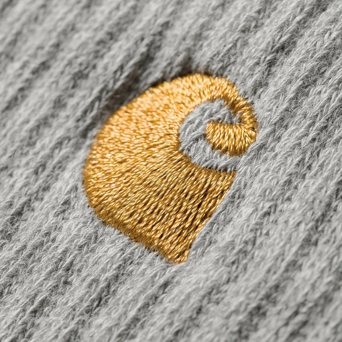 Gros plan sur la maille gris chiné d'une chaussette Chase et sur son logo C brodé en fil doré brillant