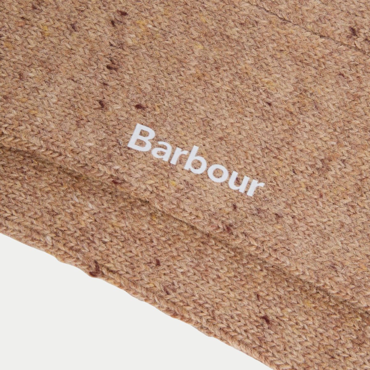 Gros plan sur la laine beige sable semée de neps bordeaux, logo Barbour blanc brodé sur la tige.