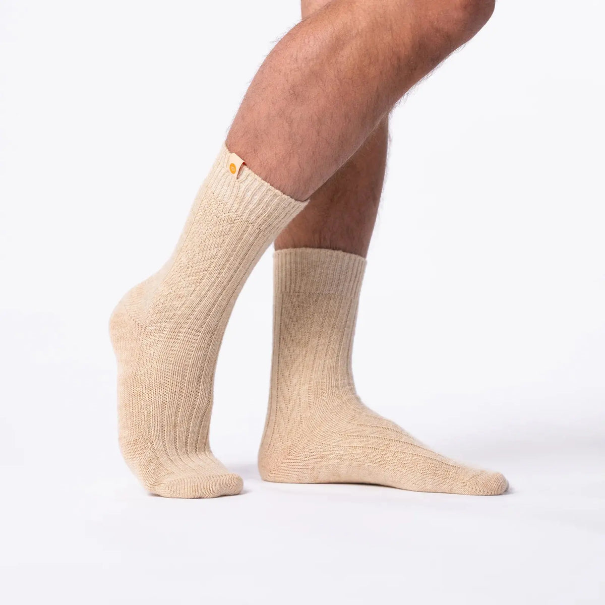 Chaussettes en laine écrue portées debout, relief des côtes larges et du damier tricoté sur le coup de pied