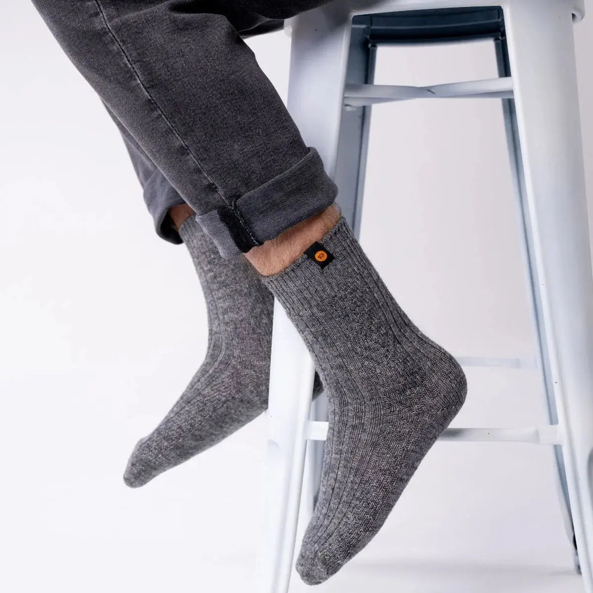 Chaussettes en laine gris chiné portées jambes croisées, maille épaisse et bord-côte souple sous le jean