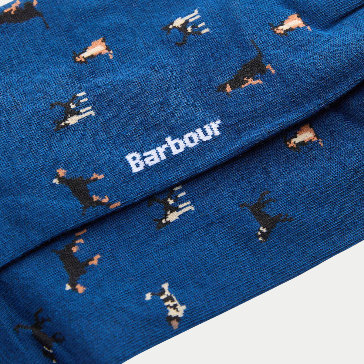 Gros plan sur la maille bleu roi : chiens tricotés en intarsia et logo Barbour blanc au milieu de la tige