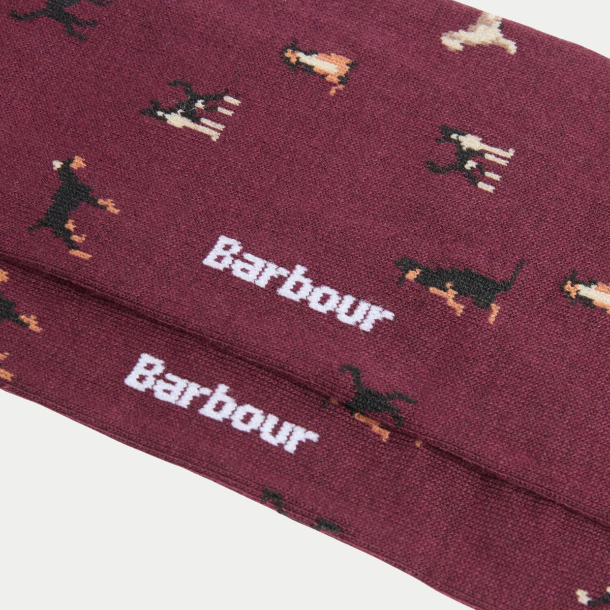Gros plan sur la maille bordeaux chinée : chiens noir et fauve en intarsia et deux logos Barbour blancs