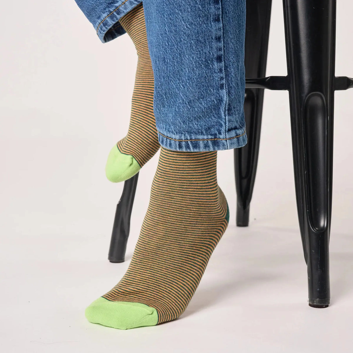 Paire rayée vert sapin et ocre portée avec un jean, pointes vert anis bien détachées sur les deux pieds.