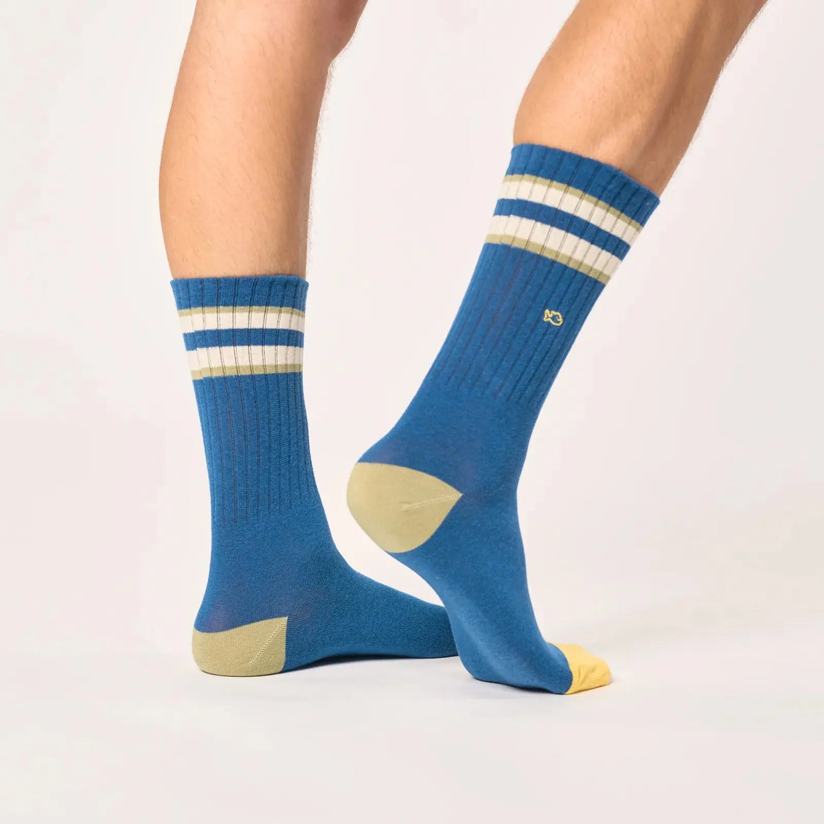 Chaussettes bleu pétrole de trois quarts arrière, talon kaki clair, pointe jaune et bandes ivoire en haut.