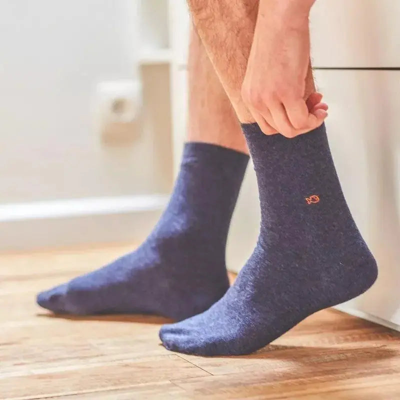 Paire Bleu Marine chiné portée sur un parquet, maille unie sans talon contrasté et poisson brodé orange.