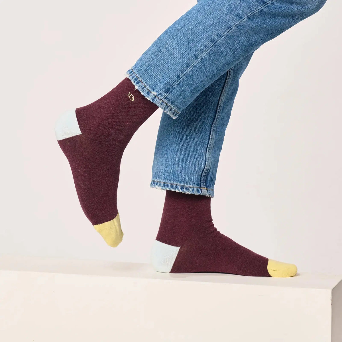 Paire bordeaux chiné portée jambe levée, talon bleu givré et pointe jaune pâle nettement détachés.
