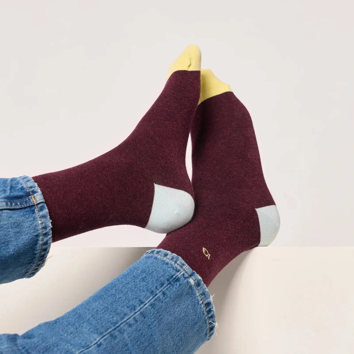 Chaussettes bordeaux chiné vues semelles relevées, talons bleu givré, pointes jaune pâle et poisson écru.