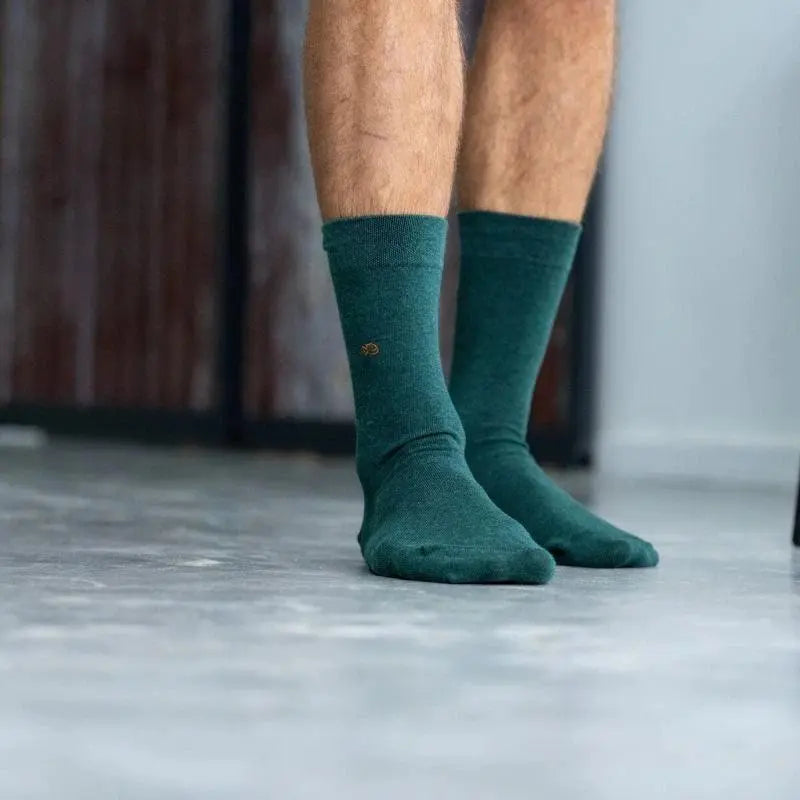 Chaussettes vert anglais portées de face sur sol béton, broderie poisson orange visible