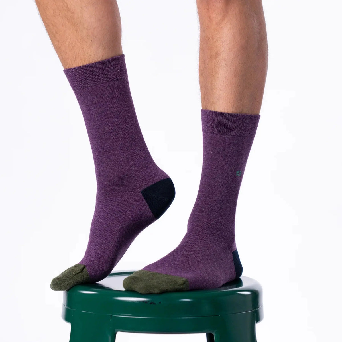Chaussettes violet prune portées sur un tabouret vert, talon bleu marine et pointes kaki