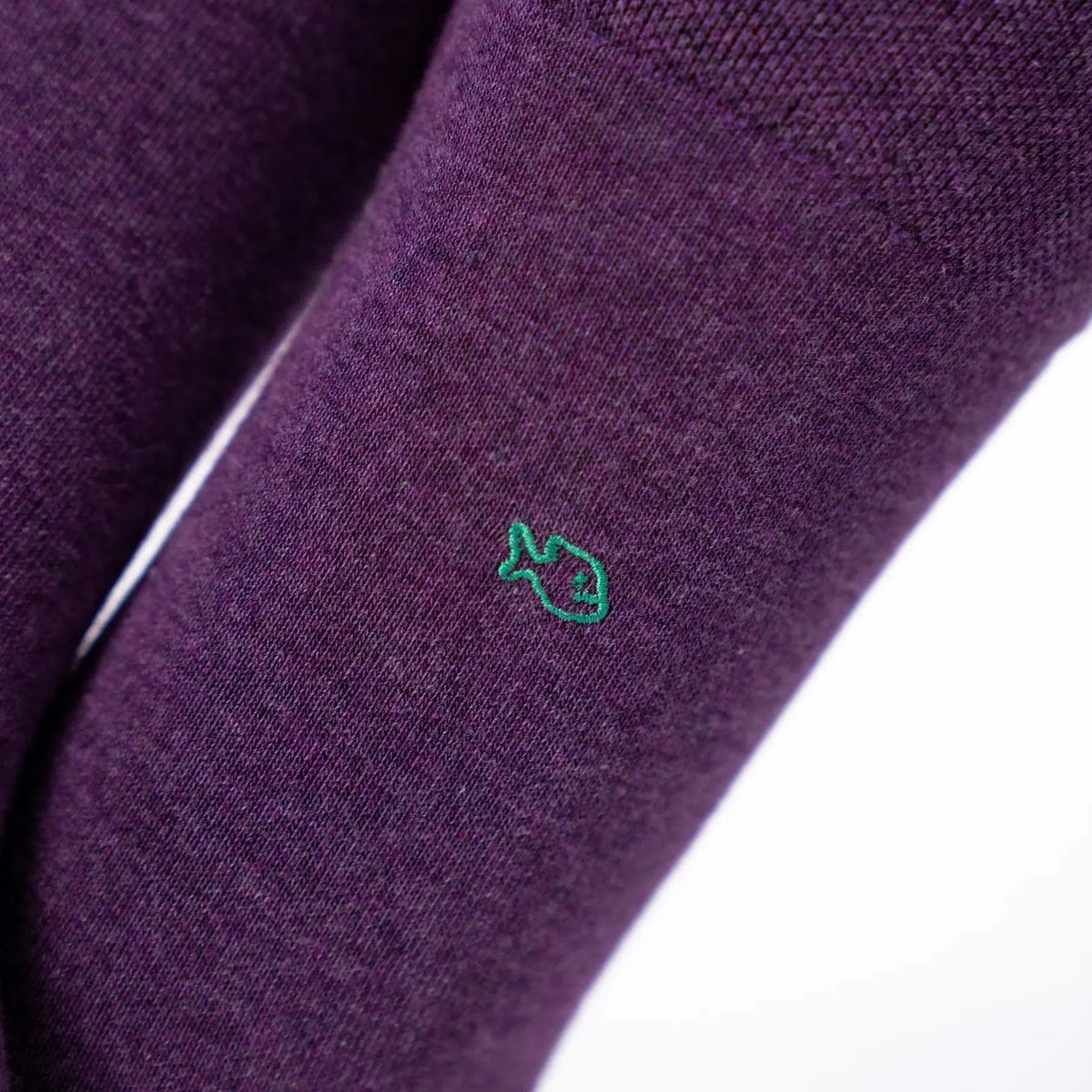 Macro sur la maille violet prune chinée et le poisson brodé vert sapin
