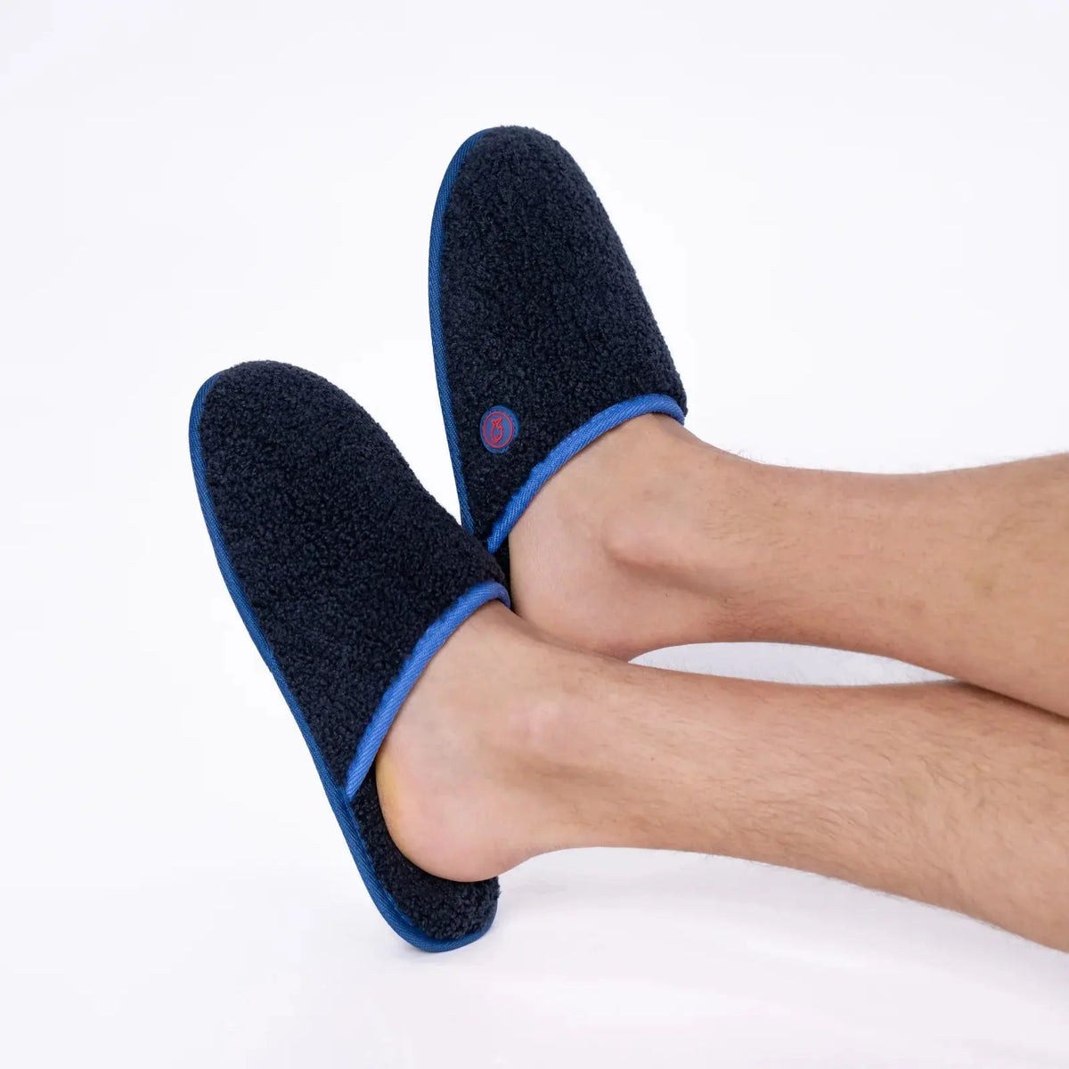 Chaussons en sherpa Bleu Marine portés aux deux pieds, talon ouvert et bordure bleu roi bien visibles