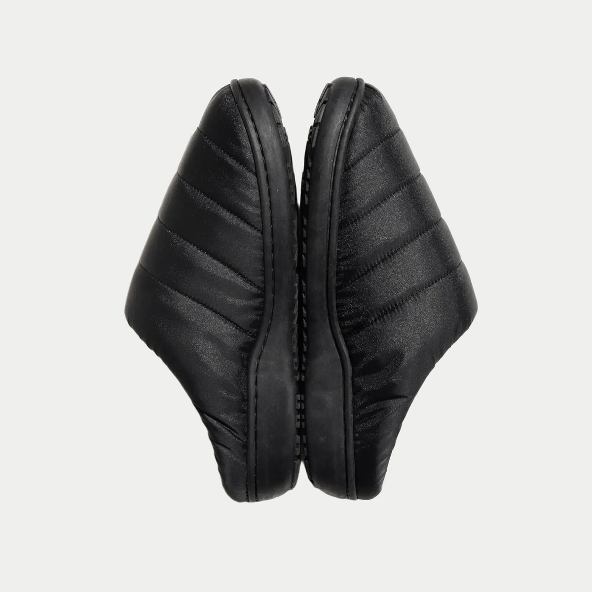 Paire de chaussons noirs dressée côte à côte, flancs matelassés et tranche de semelle apparente