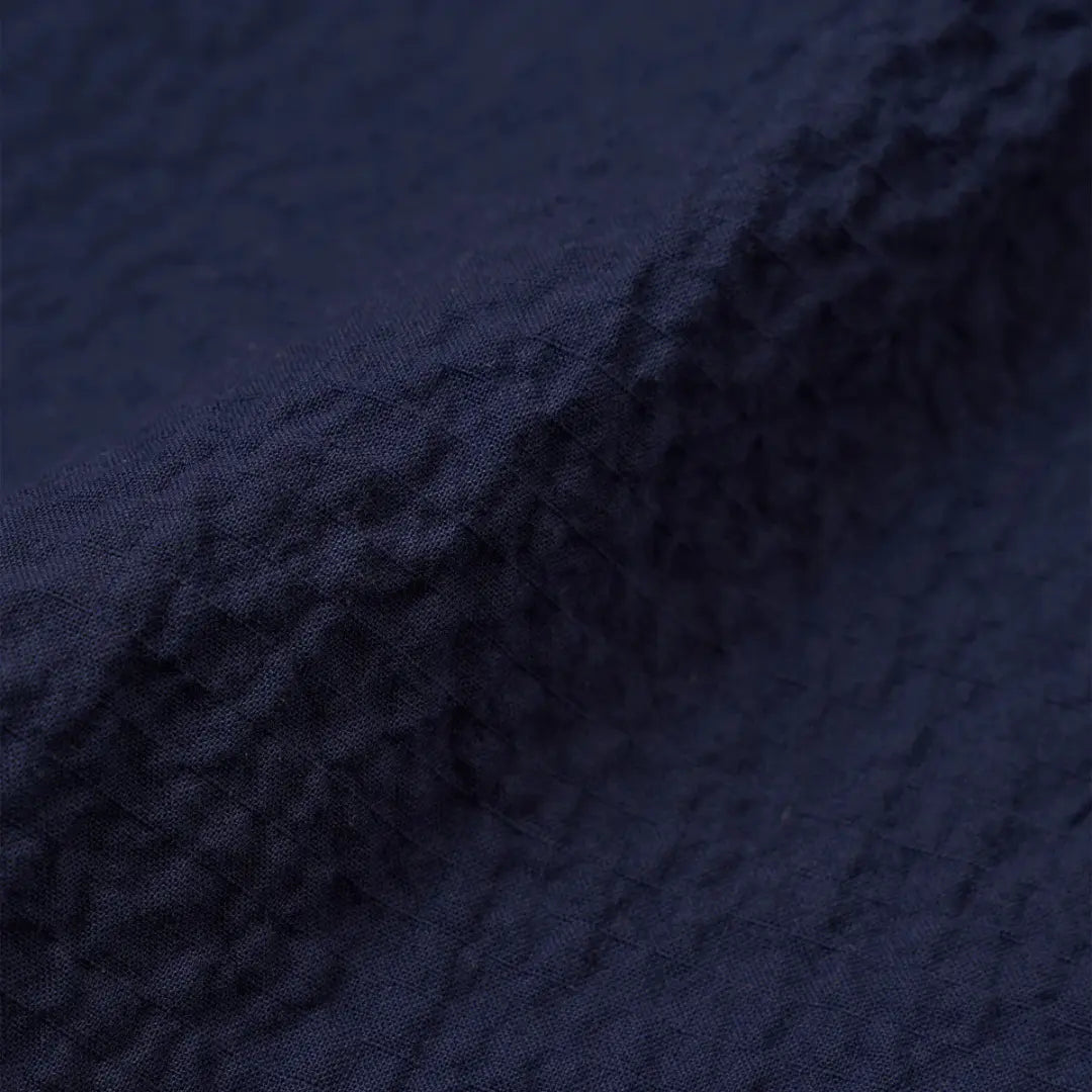 Macro du tissu bleu marine de la chemise Attendant, coton au relief gaufré façon crépon