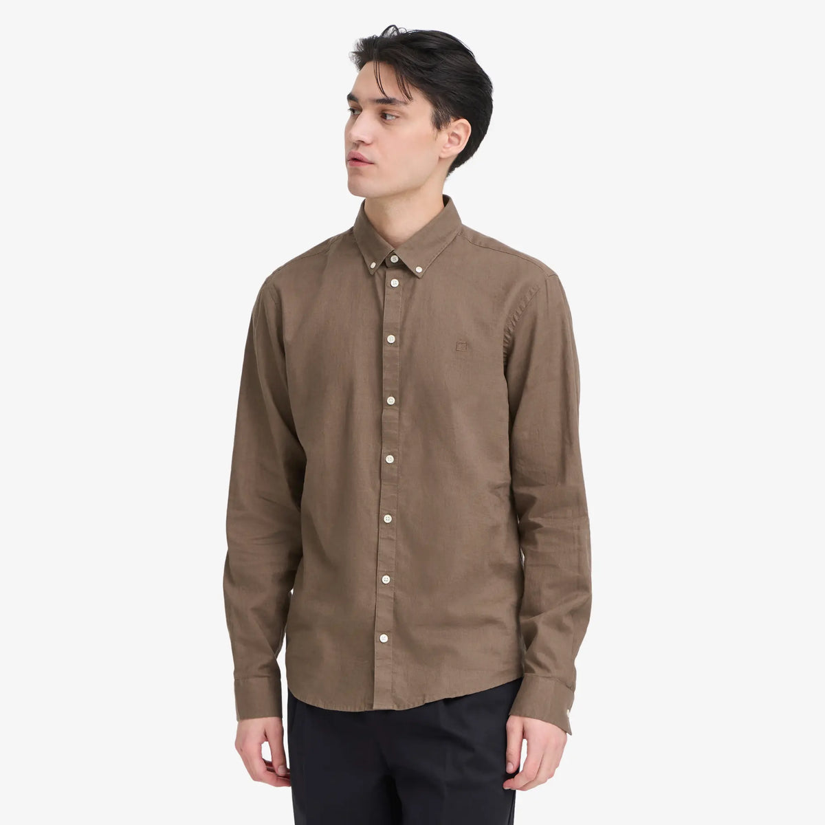 Chemise en lin marron portée sur un pantalon noir, tombé fluide et manches longues