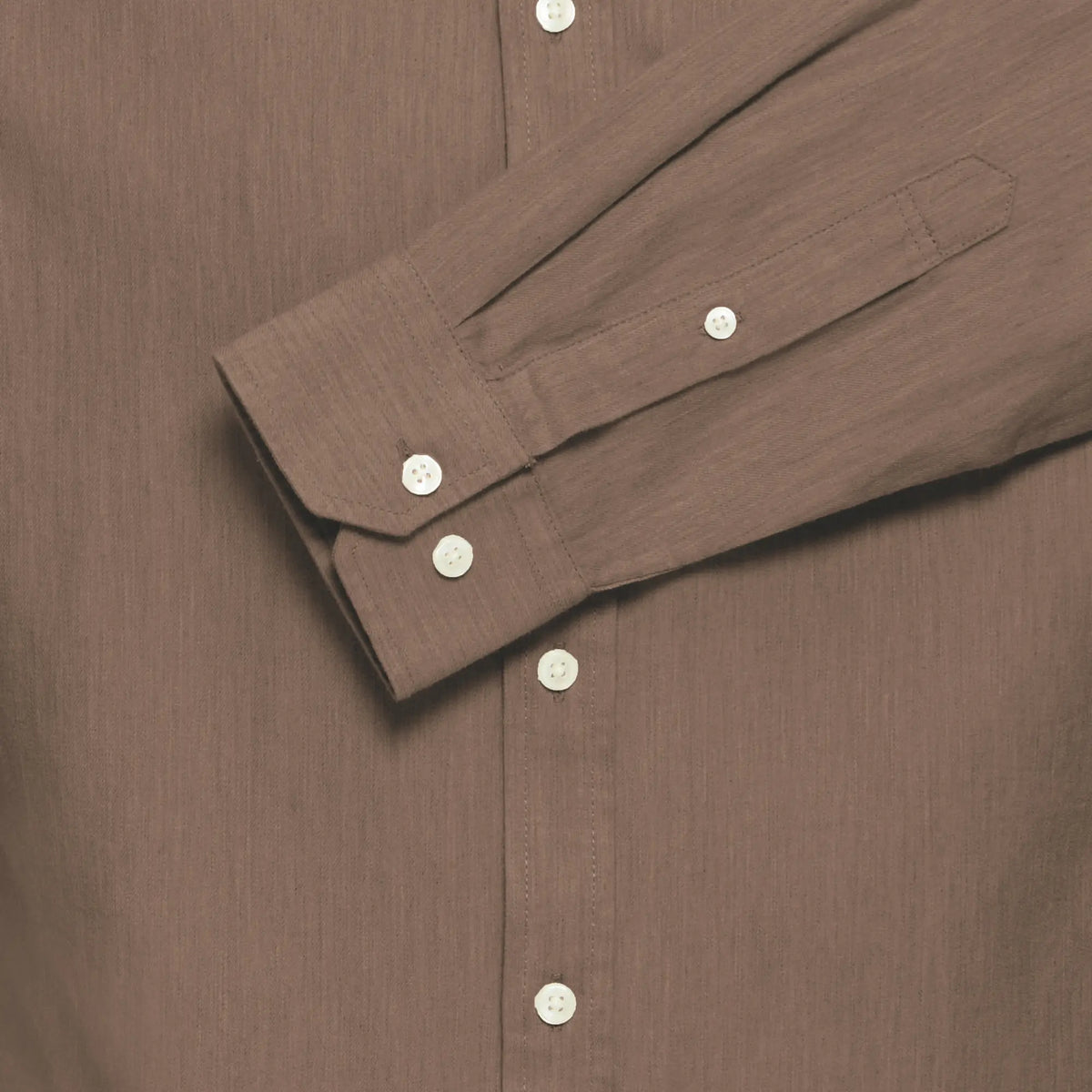 Gros plan du poignet boutonné et de la patte de manche, grain de lin bien visible