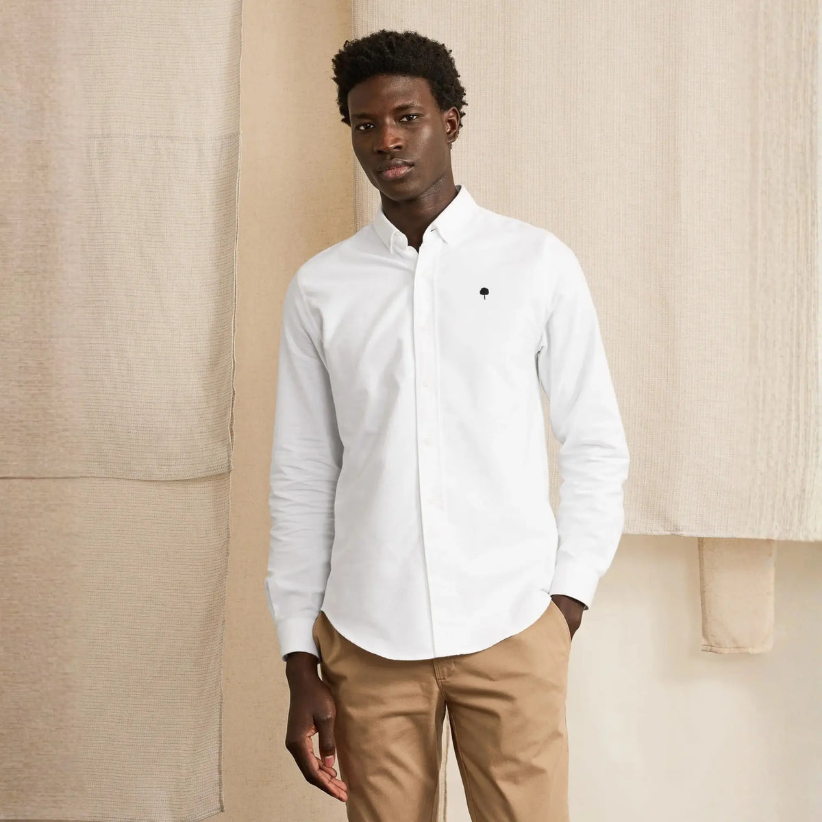 Chemise Ivoy écrue portée de face, boutonnée jusqu'au col sur un pantalon beige