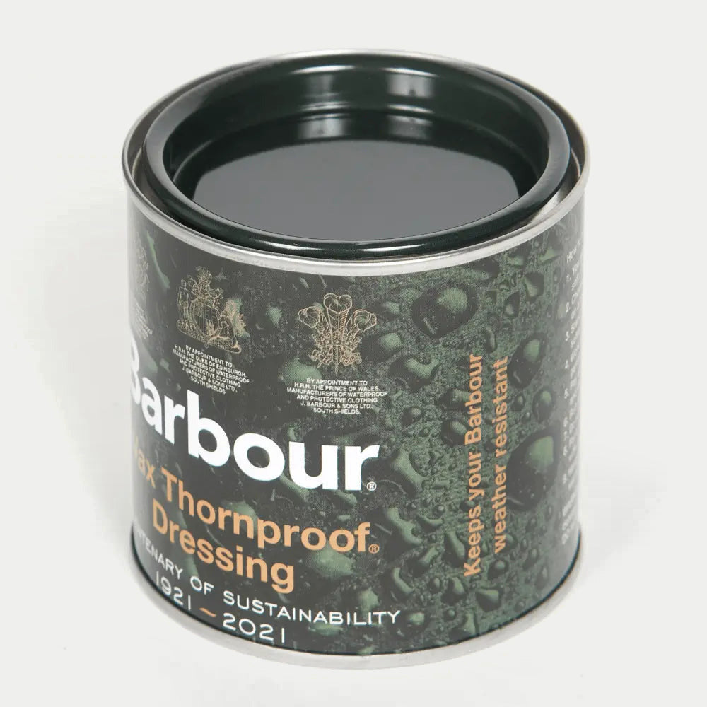 Pot de cire Barbour ouvert de trois quarts, couvercle retiré : surface de cire vert très sombre et bord métal