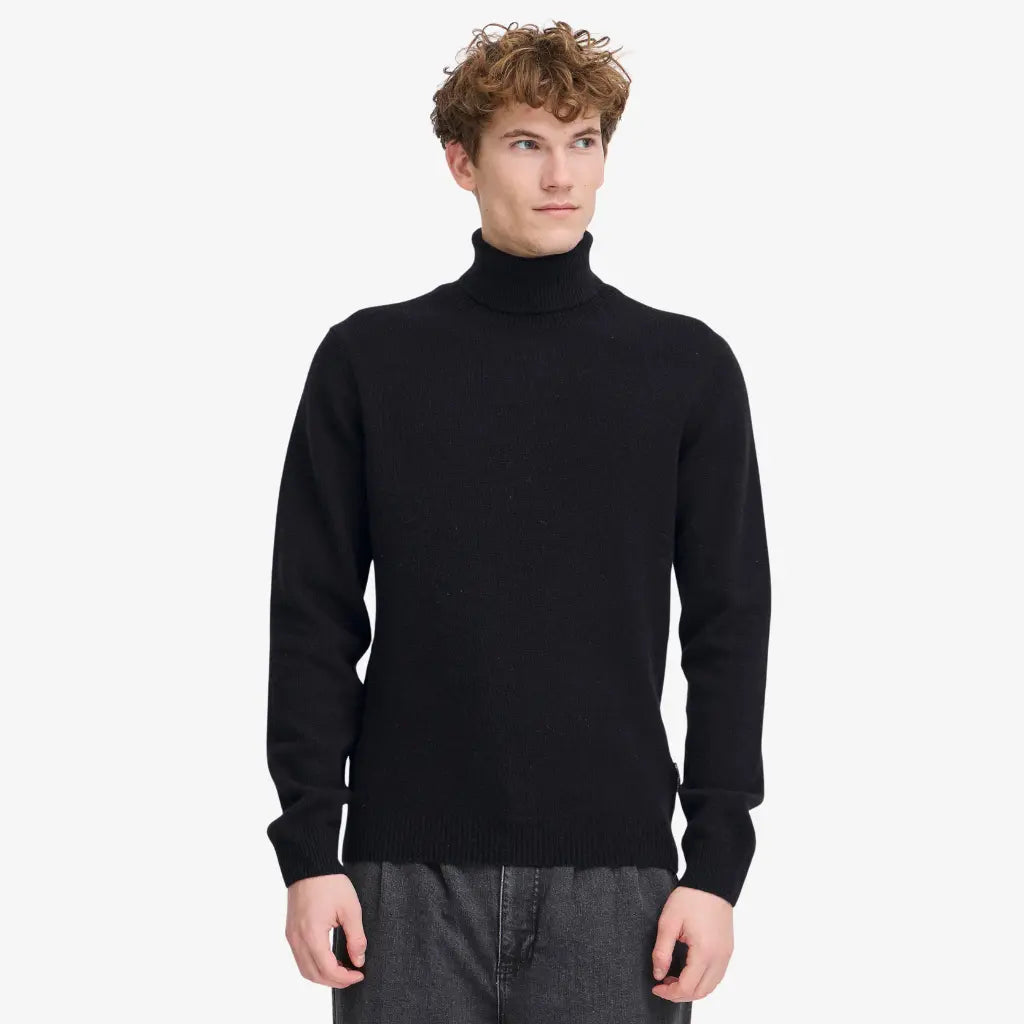 Col Roulé noir porté, maille mate et bord-côte de taille retombant sur un jean gris