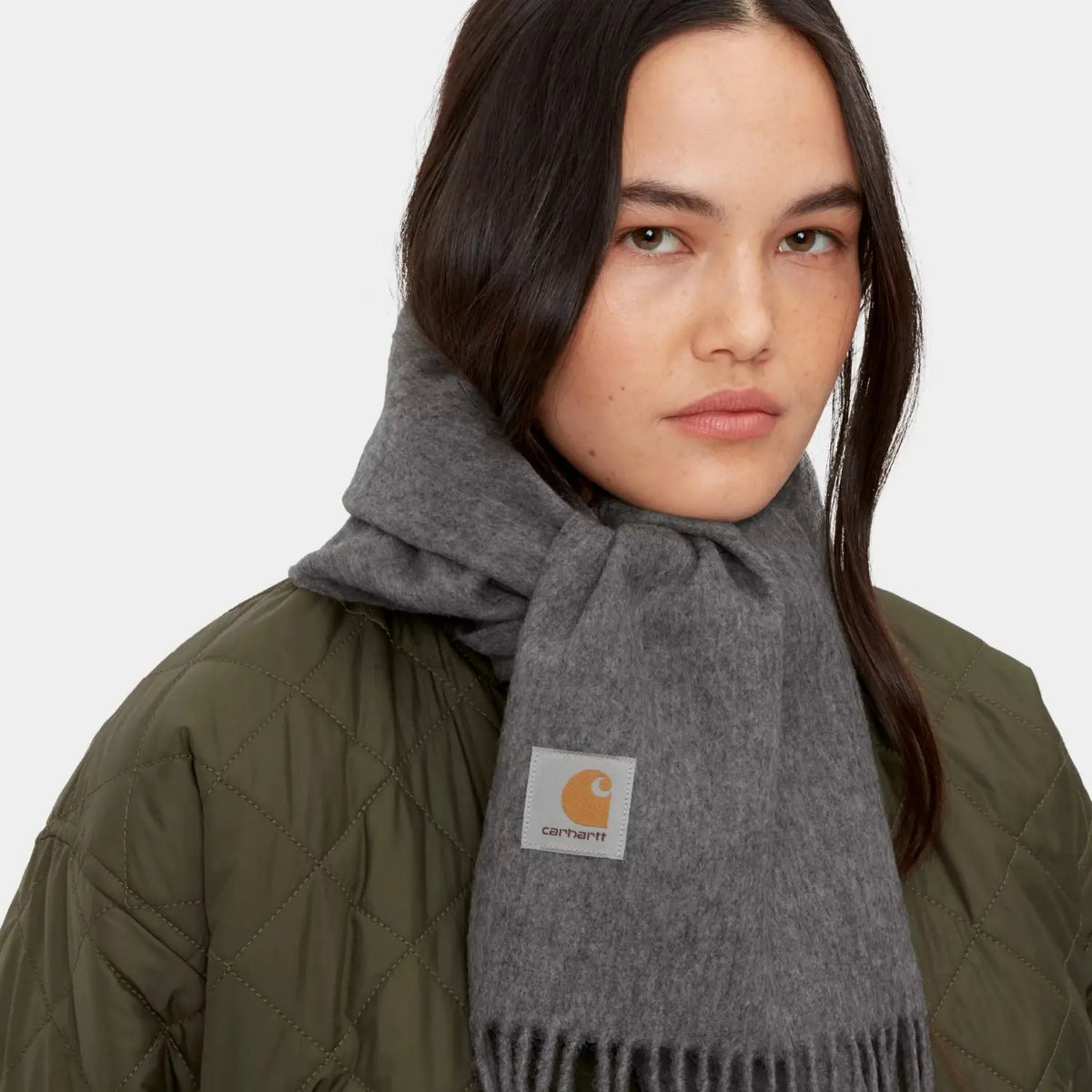 Écharpe Clan Scarf gris chiné portée nouée au cou, pan avant marqué de l'étiquette logo carrée blanche