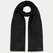 Écharpe en laine noire enroulée, longs pans frangés et petite plaquette métal