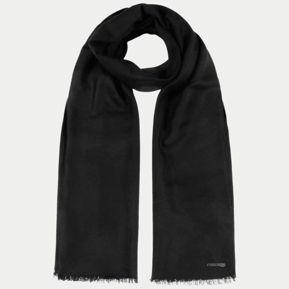 Écharpe en laine noire enroulée, longs pans frangés et petite plaquette métal
