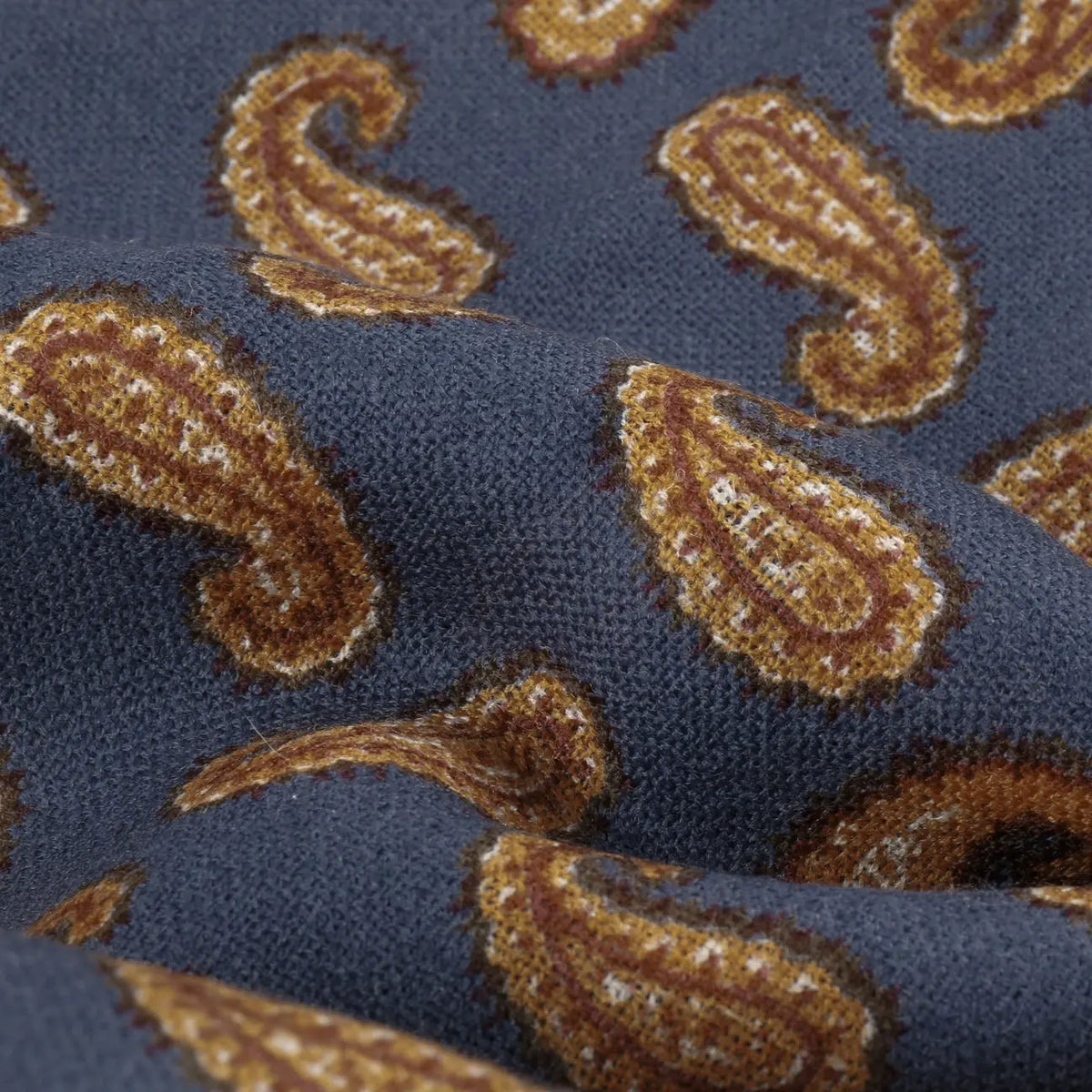 Macro de la laine : motifs paisley ocre et bordeaux sur fond bleu marine