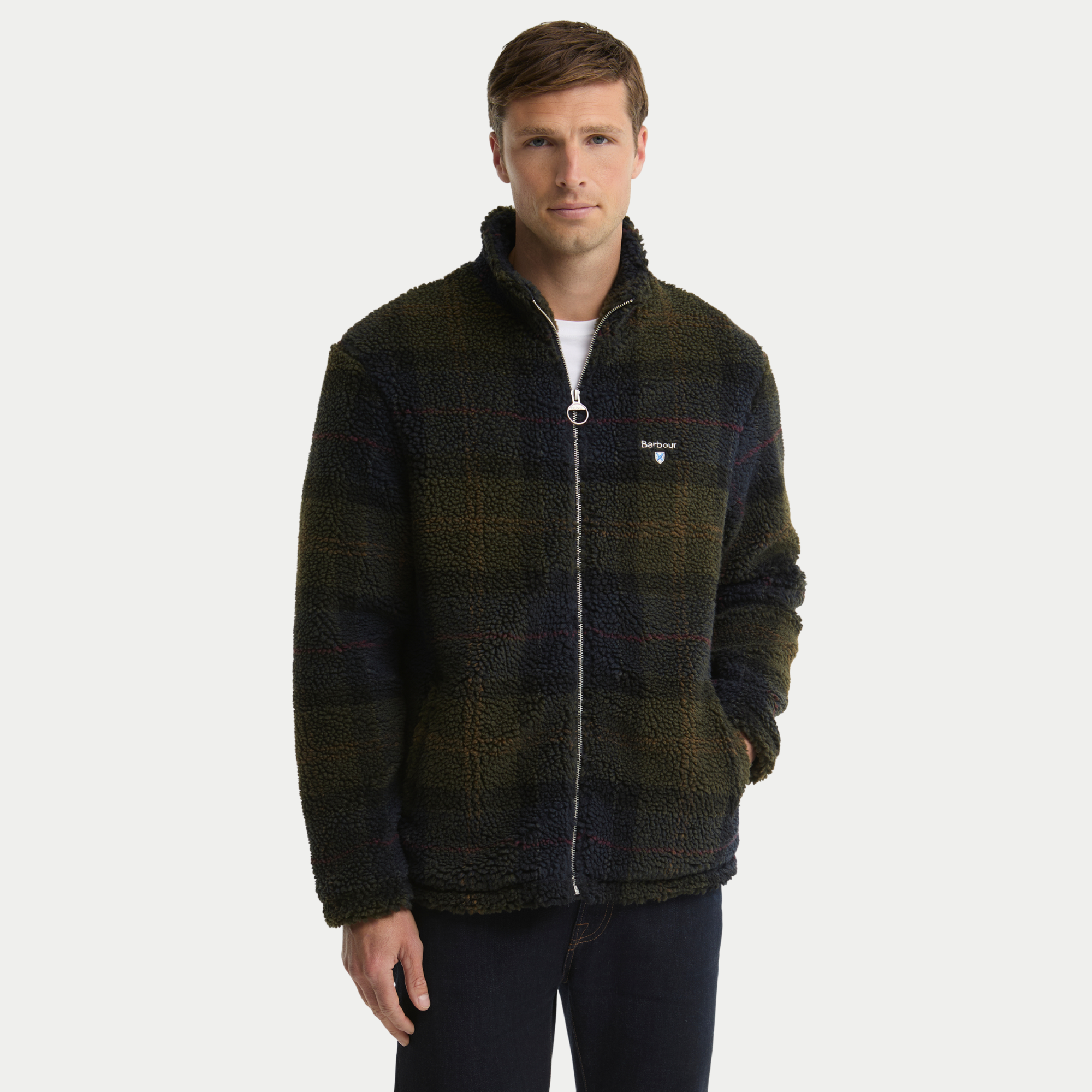 Polaire sherpa Barbour tartan olive foncé portée, zip entrouvert sur t-shirt blanc, une main en poche