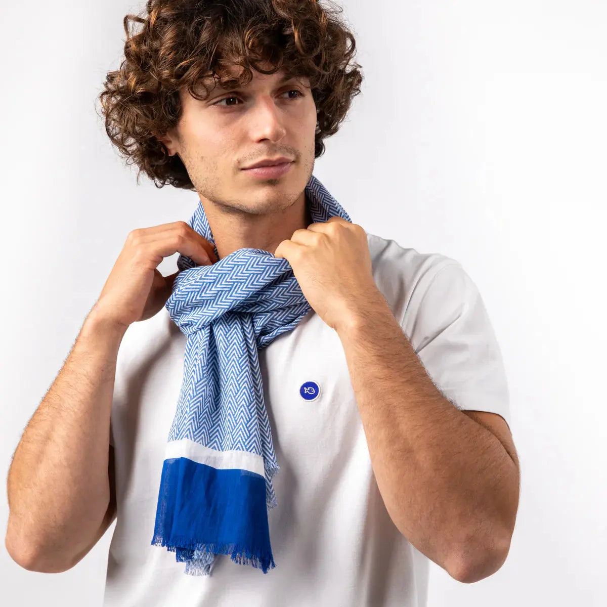 Foulard à chevrons bleus et blancs noué autour du cou, les deux pans retombant droit devant le buste