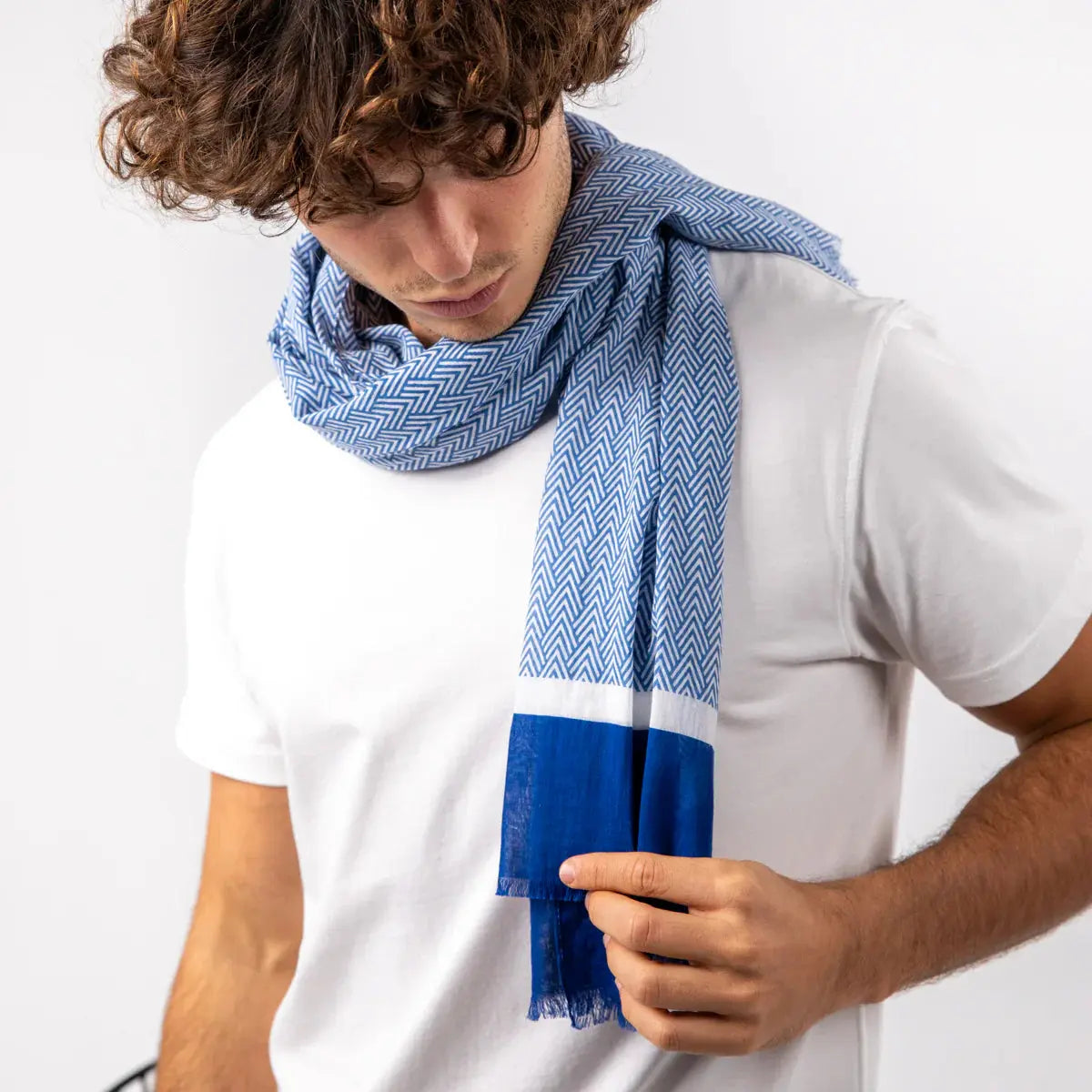 Foulard à chevrons bleus enroulé en double tour autour du cou, extrémité bleu roi frangée bien visible